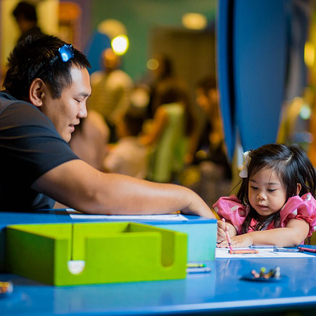 Un padre y su hija muy pequeña coloreando en una mesa del Discovery Children&#039;s Museum