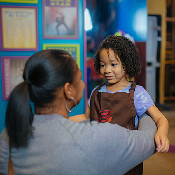 a young african american girl looking into her mother's face and being half-hugged