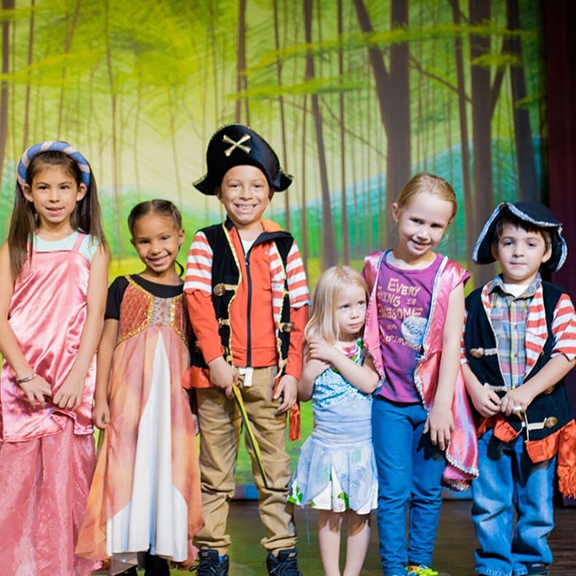 Kids dressed in gowns & as pirates standing on a stage