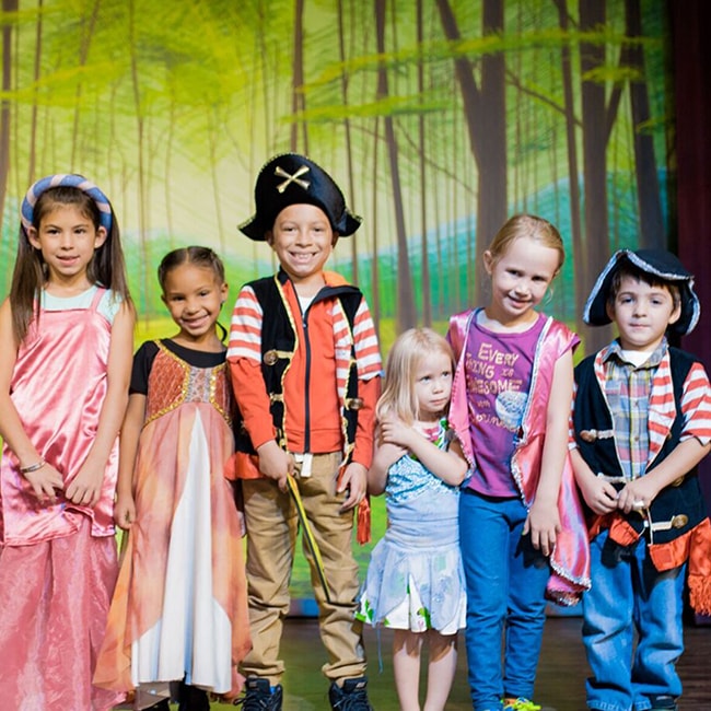 Kids dressed in gowns & as pirates standing on a stage