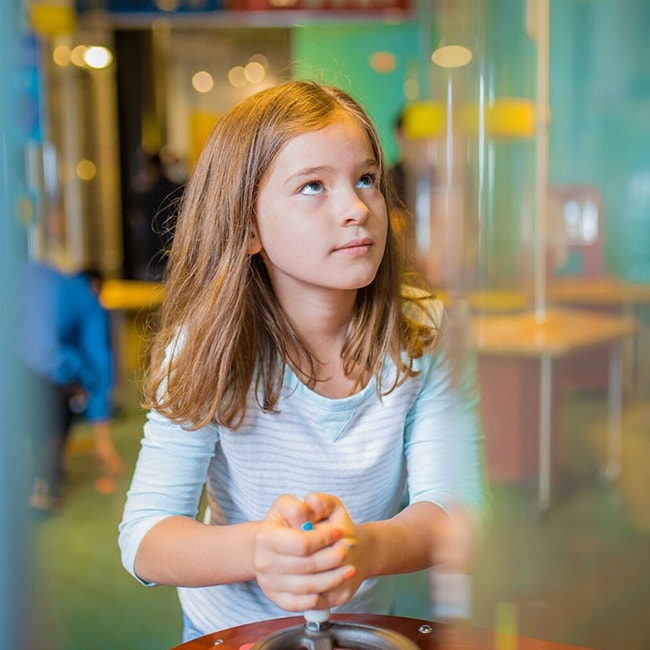 Una niña mira un juego fuera de cámara para estimular la curiosidad y la resolución de problemas