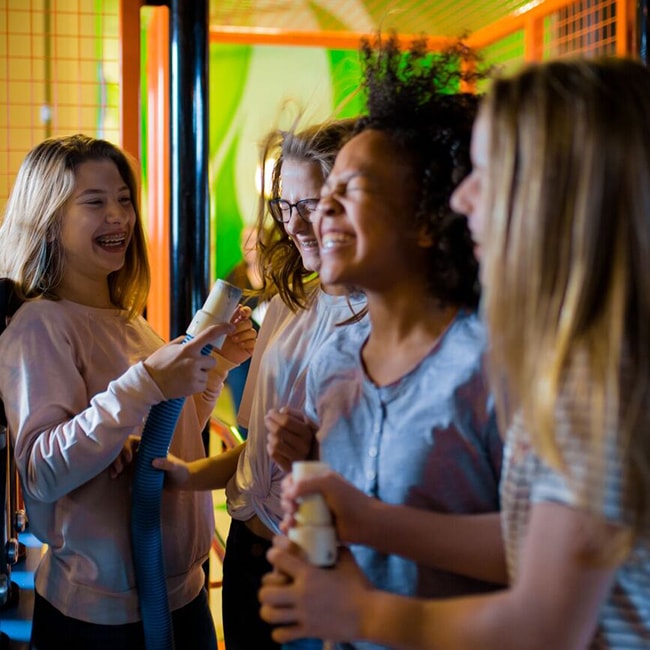 Young female kids having fun in the museum. One kid is holding a hose that blows air