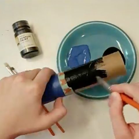 A lightsaber hilt made of paper towel tubes being painted