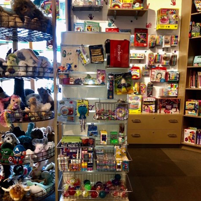 Estanterías verticales de pequeños juguetes y peluches en la tienda de regalos del Discovery Children&#039;s Museum.