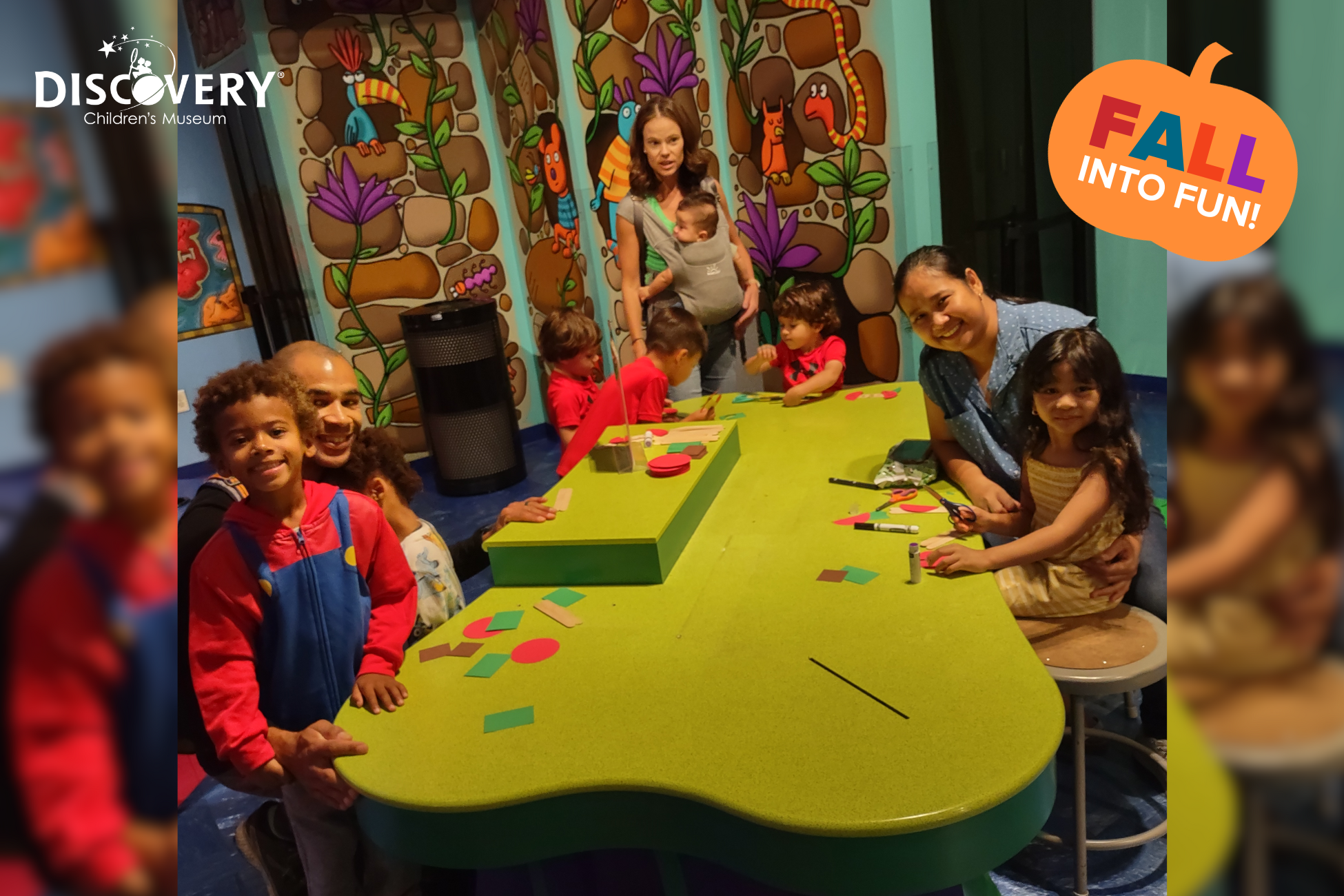3 families with small children at a long green crafts table posing for a photo at the Discovery Children's Museum