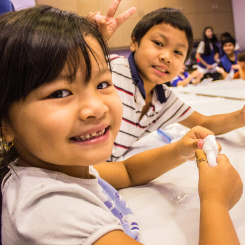 2 niños sosteniendo slime en una mesa y posando para una foto en un campamento de verano del Discovery Children&#039;s Museum.