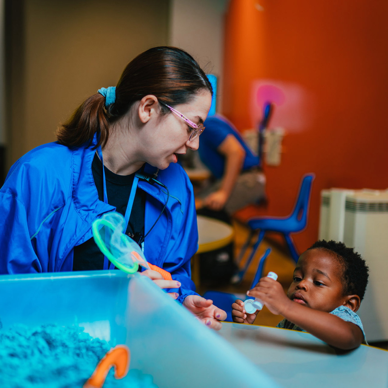 A docent helping a young child who is inspecting an object at the Discovery Children's Museum